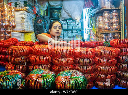 Donna indiana vendendo schiave in un piccolo negozio al piano seminterrato del KR il mercato dei fiori di Bangalore in India che è uno dei più grandi mercati di fiori in Asia Foto Stock