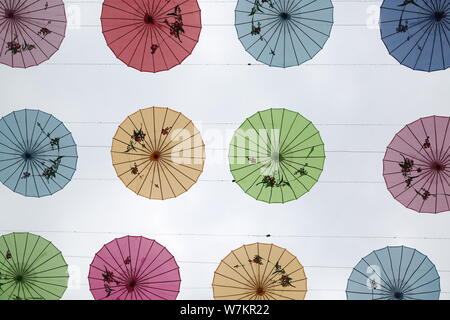 Olio colorato-ombrelli di carta appeso in aria su una strada di Ji'nan city, est della Cina di provincia di Shandong, 2 agosto 2017. Olio colorato-ombrelli di carta Foto Stock