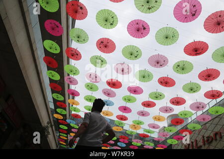 Un pedone passeggiate sotto olio colorato-ombrelli di carta lungo una strada di Ji'nan city, est della Cina di provincia di Shandong, 2 agosto 2017. Olio colorato-pap Foto Stock