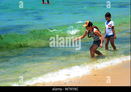 I turisti hanno divertimento nell'acqua inquinata con alghe blu-verde fiore a un beach resort nella città di Sanya, Cina del sud della provincia di Hainan, 21 agosto 2017. Foto Stock
