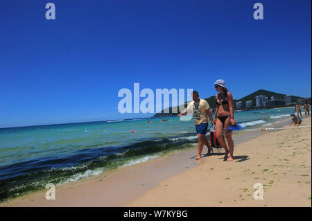 I turisti hanno divertimento nell'acqua inquinata con alghe blu-verde fiore a un beach resort nella città di Sanya, Cina del sud della provincia di Hainan, 21 agosto 2017. Foto Stock