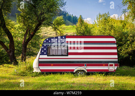 Un auto rimorchio, un motore home, dipinta nella bandiera nazionale degli Stati Uniti d'America sta parcheggiato in una montagna. Il concetto di trasporto su strada, il commercio, l'esportazione e imp Foto Stock