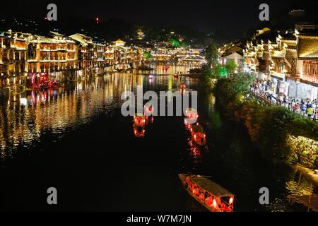 I turisti prendere barche lungo il fiume Tuojiang (tuo fiume) in Fenghuang antica città scenic area di notte nella contea di Fenghuang, Xiangxi Tujia e Mia Foto Stock