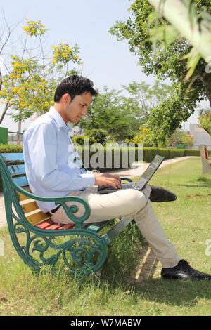 Young man working on laptop in a park Stock Photo