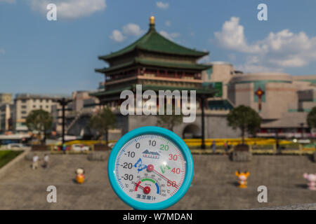 Un residente locale visualizza un termometro che mostra la temperatura attuale di raggiungere 49 gradi Celsius in un bruciante giorno di fronte al Xi'an Bell Towe Foto Stock