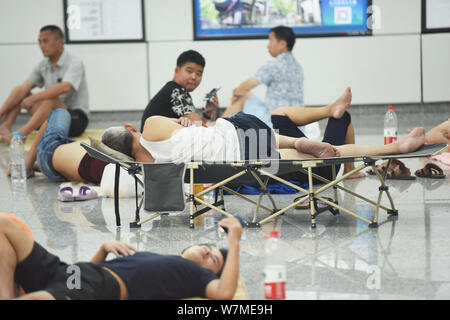 La gente di riposo in un'aria condizionata la stazione della metropolitana di sfuggire al caldo su un bruciante giorno nella città di Hangzhou, a est della Cina di provincia dello Zhejiang, 22 luglio 2017. Foto Stock