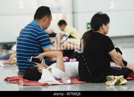 La gente di riposo in un'aria condizionata la stazione della metropolitana di sfuggire al caldo su un bruciante giorno nella città di Hangzhou, a est della Cina di provincia dello Zhejiang, 22 luglio 2017. Foto Stock