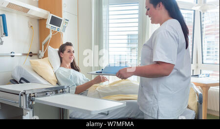 Infermiere portando la donna pasto del paziente sul letto di ospedale Foto Stock
