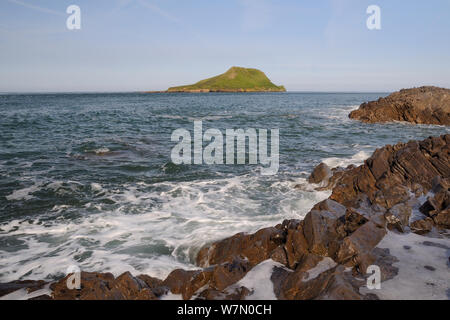 Rocce calcaree lavato mediante onde con la vite senza fine la testa in background, tagliati fuori dal continente come un isola ad alta marea, Rhossili, La Penisola di Gower, Wales, Regno Unito, Luglio. La sequenza 2 di 3 a differenti maree Foto Stock