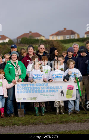 I bambini, i volontari e i membri della comunità di piantagione di alberi parte progetto di spazi di respirazione progetto nella zona svantaggiata di Swansea con striscioni, Wales, Regno Unito, dicembre 2009 Foto Stock