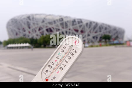 Un residente locale visualizza un termometro che mostra la temperatura attuale di raggiungere 40 gradi Celsius in un bruciante giorno di fronte la Nationa di Pechino Foto Stock