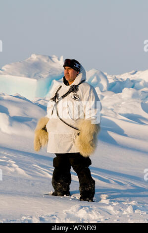 L'uomo indossando il tradizionale polare guanti bearskin sorge sulla banchisa oltre il mare Chukchi. Dagli impianti offshore di Barrow, Arctic costa di Alaska, molla, maggio 2012. Foto Stock