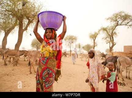 Gula donna di fresco con acqua aspirata dal pozzetto. Queste persone sono Maghreb Arabo originariamente discendenti dal Sudan. Preziosa acqua è prelevato da un bene comune ogni giorno da donne e bambini in Kashkasha villaggio nei pressi di Zakouma National Park, Ciad 2010 Foto Stock