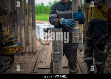 Offshore Oil Rig lavoratore Preparare utensili e attrezzature per la perforazione di pozzi petroliferi e di gas a testa pozzo piattaforma. Che compongono un tubo di trivella il collegamento. Una vista fo Foto Stock