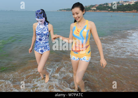 Un modello, a sinistra, che indossa un costume da bagno facekini dotate di blu e bianco porcellana e ricamo è raffigurato in un resort sulla spiaggia nella città di Qingdao, Cina orientale Foto Stock