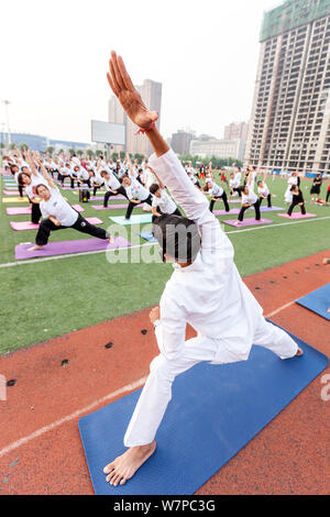 Gli appassionati cinesi vestite di bianco eseguire lo yoga sotto la guida dei maestri yoga indiano Shitanshu Sharma e Jitendra Kumawat per contrassegnare il Inte Foto Stock