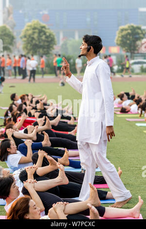 Gli appassionati cinesi vestite di bianco eseguire lo yoga sotto la guida dei maestri yoga indiano Shitanshu Sharma e Jitendra Kumawat per contrassegnare il Inte Foto Stock