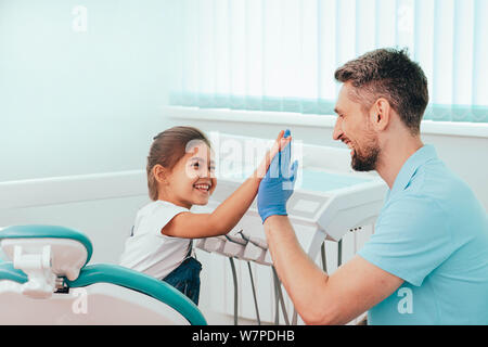 Bambino visita dal dentista. Ridere bambina sono cinque al dentista presso la clinica dentale Foto Stock