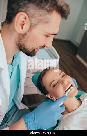 Donna di ottenere la rimozione della placca con apparecchiatura dentale dal suo dentista presso la clinica Foto Stock