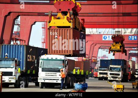 Una gru ponti sollevatori di veicoli contenitori per essere spediti all'estero da parte dei camion su una banchina del porto di Qingdao nella città di Qingdao, Cina orientale della provincia di Shandong, 7 Foto Stock