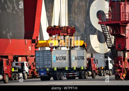 Una gru ponti sollevatori di veicoli contenitori per essere spediti all'estero da parte dei camion su una banchina del porto di Qingdao nella città di Qingdao, Cina orientale della provincia di Shandong, 7 Foto Stock