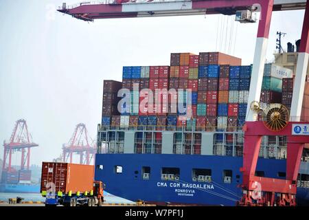 Una gru ponti sollevatori di veicoli contenitori per essere spediti all'estero da parte dei camion su una banchina del porto di Qingdao nella città di Qingdao, Cina orientale della provincia di Shandong, 7 Foto Stock