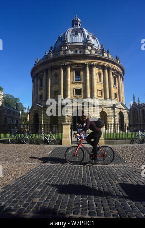 Inghilterra, Oxford, biblioteca Bodleian, Radcliffe Camera con ciclista passante. Foto Stock