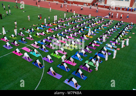 Gli appassionati cinesi vestite di bianco eseguire lo yoga sotto la guida dei maestri yoga indiano Shitanshu Sharma e Jitendra Kumawat per contrassegnare il Inte Foto Stock