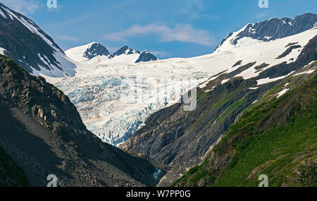 Primo piano di un ghiacciaio in Alaska vicino a portage e whittier circondato da montagne e con il cielo blu e nuvole gonfi in background Foto Stock