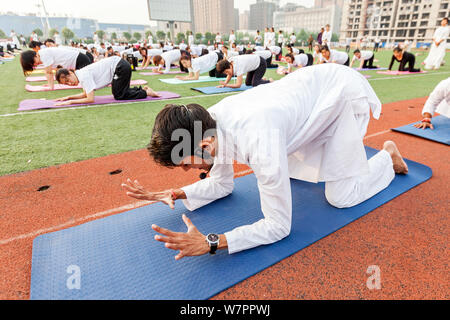 Gli appassionati cinesi vestite di bianco eseguire lo yoga sotto la guida dei maestri yoga indiano Shitanshu Sharma e Jitendra Kumawat per contrassegnare il Inte Foto Stock