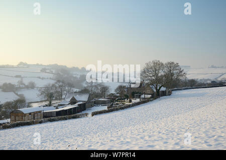 Coperta di neve campo arato, edifici agricoli e pascoli in collina nel tardo pomeriggio di luce, Tadwick, vasca da bagno e nel nord-est Somerset, Regno Unito, Gennaio 2013 Foto Stock