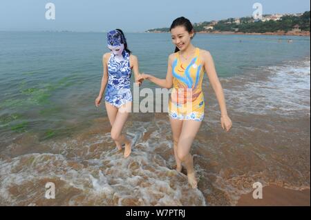 Un modello, a sinistra, che indossa un costume da bagno facekini dotate di blu e bianco porcellana e ricamo è raffigurato in un resort sulla spiaggia nella città di Qingdao, Cina orientale Foto Stock