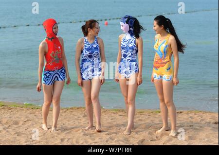 Un modello, la seconda a destra, che indossa un costume da bagno facekini dotate di blu e bianco porcellana e ricamo è raffigurato in un villaggio su una spiaggia di Qingdao City, ea Foto Stock