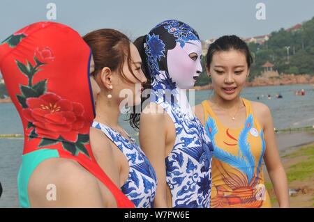Un modello, la seconda a destra, che indossa un costume da bagno facekini dotate di blu e bianco porcellana e ricamo è raffigurato in un villaggio su una spiaggia di Qingdao City, ea Foto Stock