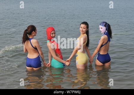 Un modello, destra, che indossa un costume da bagno facekini dotate di blu e bianco porcellana e ricamo è raffigurato in un villaggio su una spiaggia di Qingdao City East mento Foto Stock