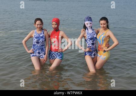 Un modello, la seconda a destra, che indossa un costume da bagno facekini dotate di blu e bianco porcellana e ricamo è raffigurato in un villaggio su una spiaggia di Qingdao City, ea Foto Stock