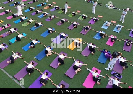 Gli appassionati cinesi vestite di bianco eseguire lo yoga sotto la guida dei maestri yoga indiano Shitanshu Sharma e Jitendra Kumawat per contrassegnare il Inte Foto Stock