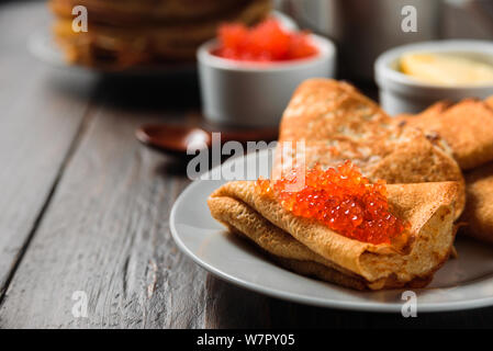 Frittelle Russe blini con caviale rosso su sfondo di legno Foto Stock