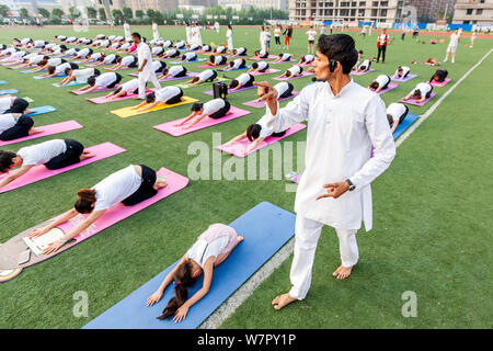 Gli appassionati cinesi vestite di bianco eseguire lo yoga sotto la guida dei maestri yoga indiano Shitanshu Sharma e Jitendra Kumawat per contrassegnare il Inte Foto Stock