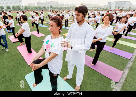 Gli appassionati cinesi vestite di bianco eseguire lo yoga sotto la guida dei maestri yoga indiano Shitanshu Sharma e Jitendra Kumawat per contrassegnare il Inte Foto Stock