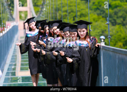 Laureate vestito in abiti accademici pongono per la laurea di foto sul ponte di vetro al Tianlongchi scenic area nella città di Pingdingshan, centrale Foto Stock