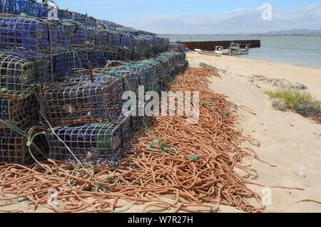 Pila di lobster pot sulla riva sabbiosa di Culatra island. Parque Natural da Ria Formosa, nei pressi di Olhao, Algarve, Portogallo, Giugno. Foto Stock