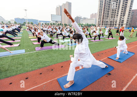 Gli appassionati cinesi vestite di bianco eseguire lo yoga sotto la guida dei maestri yoga indiano Shitanshu Sharma e Jitendra Kumawat per contrassegnare il Inte Foto Stock