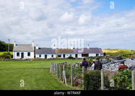 La gente che camminava sulla costa del Galles il percorso tradizionale del passato antico e pittoresco cottage. Moelfre, Isola di Anglesey (Ynys Mon), Wales, Regno Unito, Gran Bretagna Foto Stock