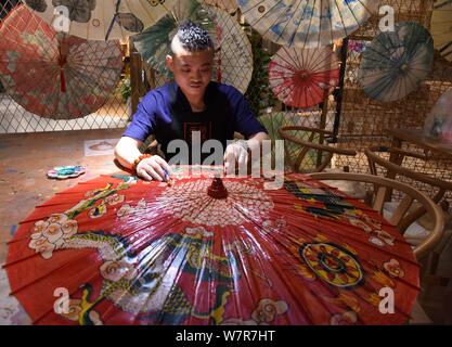 La settima generazione successore di Luzhou a olio di ombrello carta Yu Wanlun rende un olio ombrello della carta nel suo studio di Hangzhou, a est della Cina di Zhe Foto Stock