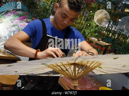 La settima generazione successore di Luzhou a olio di ombrello carta Yu Wanlun rende un olio ombrello della carta nel suo studio di Hangzhou, a est della Cina di Zhe Foto Stock