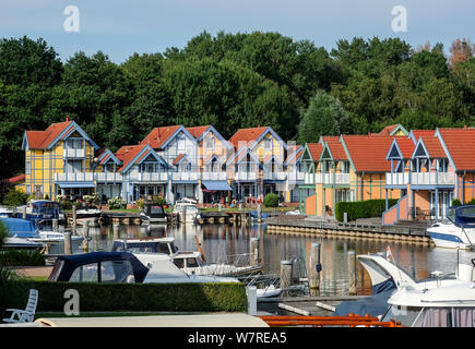 Rheinsberg, Germania. 02Aug, 2019. Il villaggio porta Rheinsberg, un marina con 208 case vacanze in Scandinavian a struttura mista in legno e muratura e stile corrispondente ormeggi per sport acquatici sul lago Rheinsberger sul lago Meclemburgo. Il complesso include un hotel a quattro stelle, un evento arena nonché strutture per lo sport e il tempo libero. Credito: Jens Kalaene/dpa-Zentralbild/ZB/dpa/Alamy Live News Foto Stock