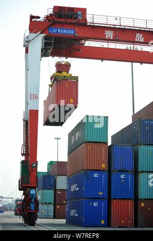 Una gru ponti sollevatori di veicoli contenitori per essere spediti all'estero da parte dei camion su una banchina del porto di Qingdao nella città di Qingdao, Cina orientale della provincia di Shandong, 7 Foto Stock