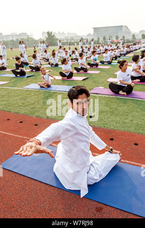 Gli appassionati cinesi vestite di bianco eseguire lo yoga sotto la guida dei maestri yoga indiano Shitanshu Sharma e Jitendra Kumawat per contrassegnare il Inte Foto Stock