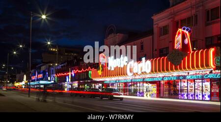 Monte Carlo, fronte spiaggia divertimento arcade di Southend on sea, Essex di notte. Sentieri di luce dal traffico su strada Foto Stock